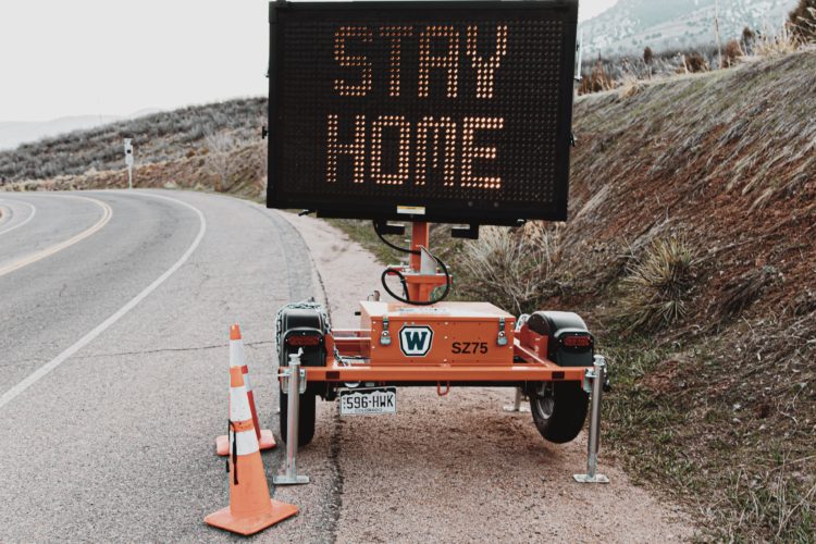 A digital sign says Stay Home on the side of an empty road.